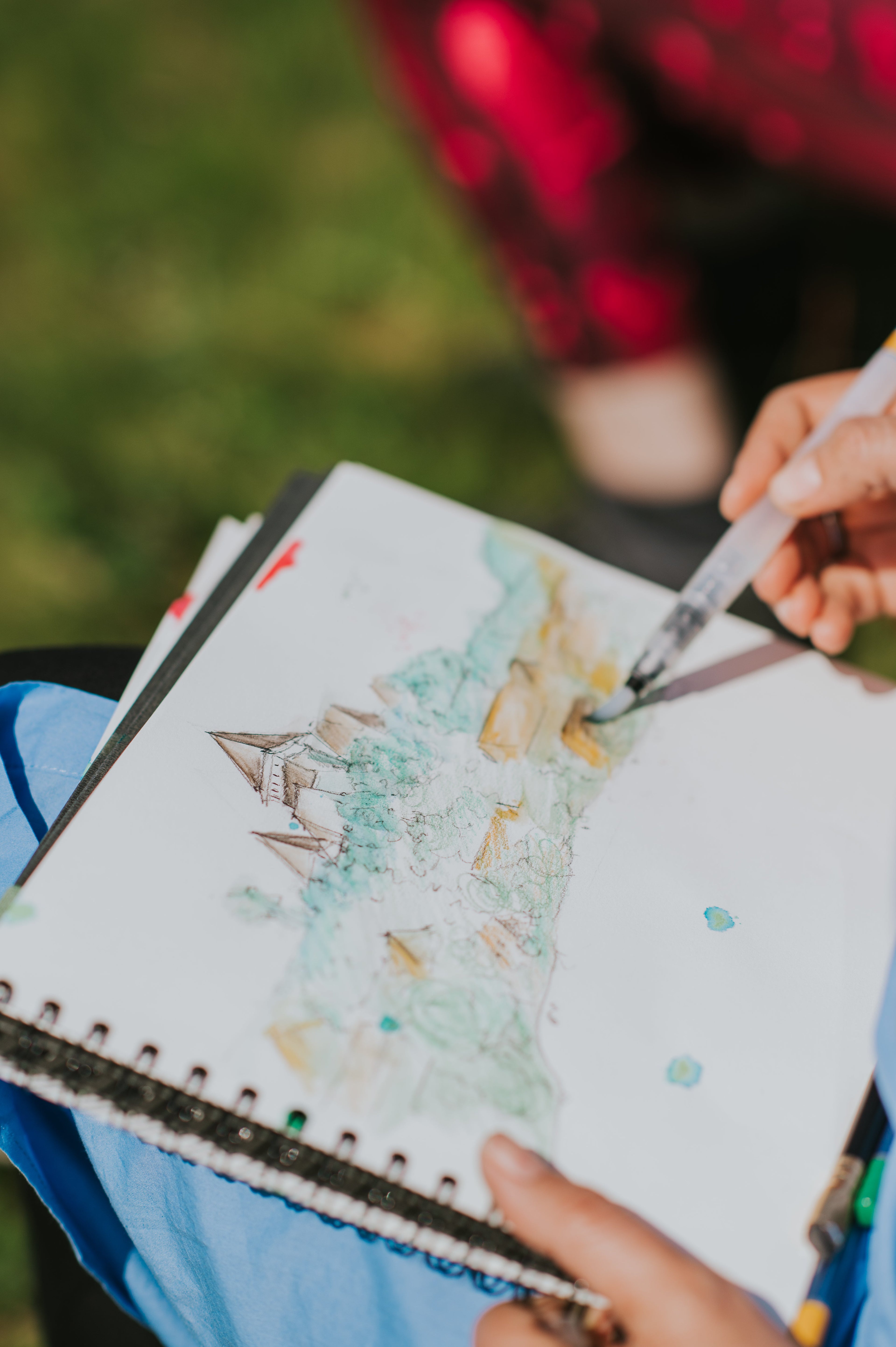 A sketchbook of one of my students while painting outdoors in Transylvania, and a half-finished watercolor featuring a fortified church over the hills